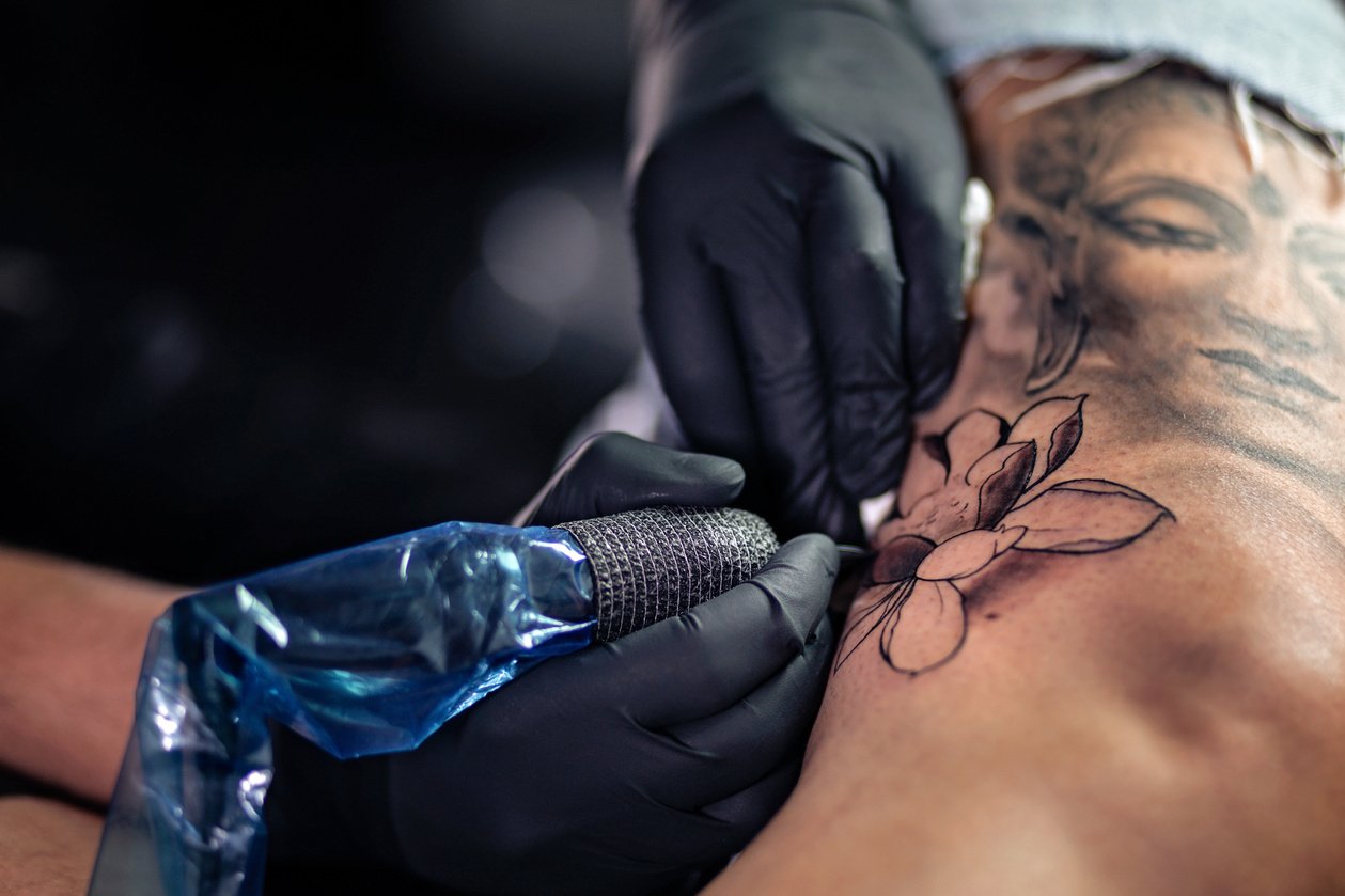 Tattoo artist making tattoo on woman leg